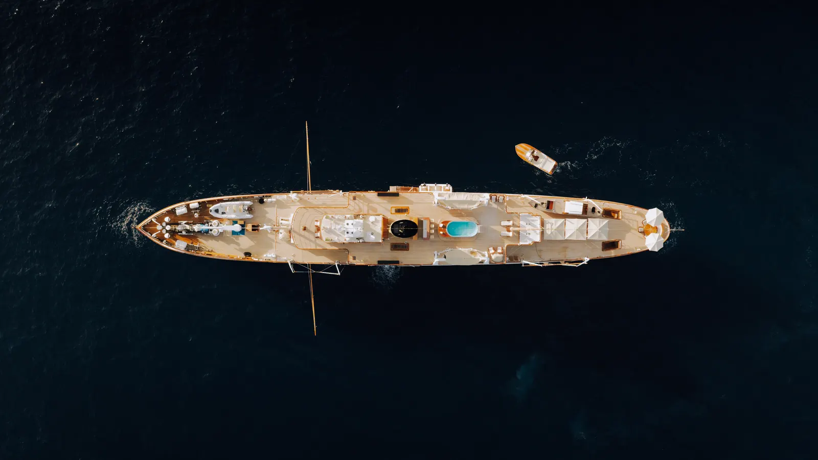 SS Delphine seen from directly overhead, her full length across open water with a tender alongside.