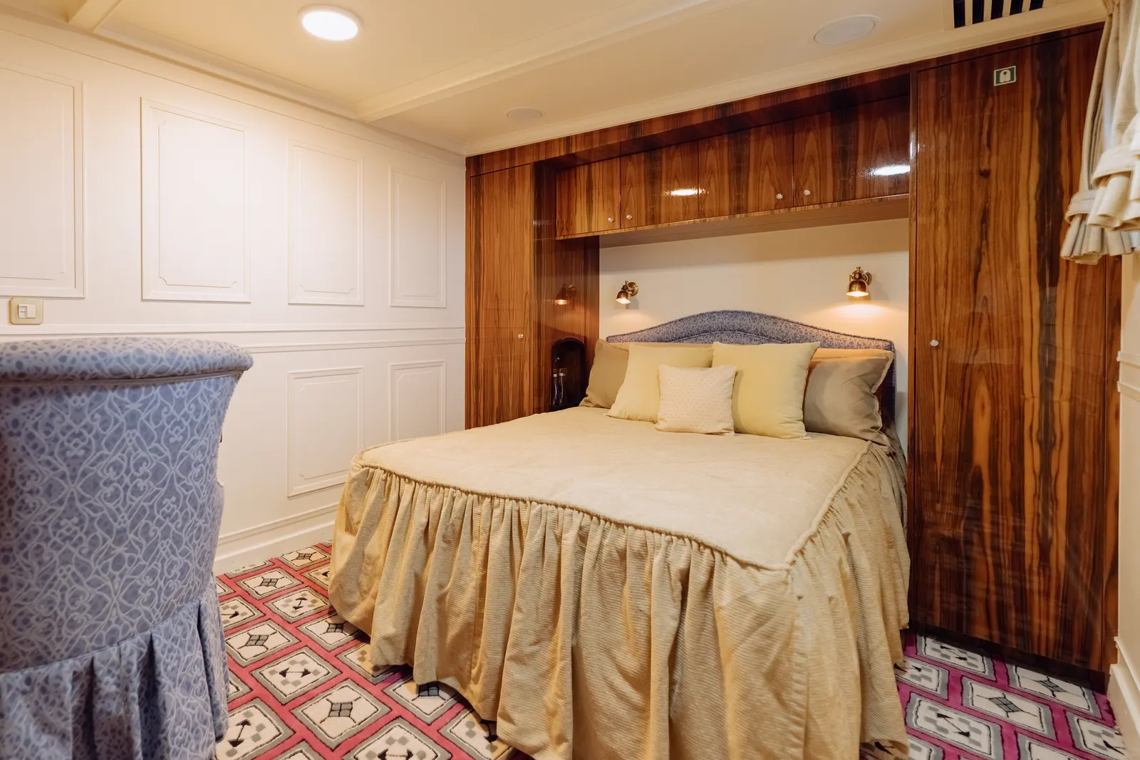 A cabin with its bed set into a mahogany alcove above a patterned carpet.