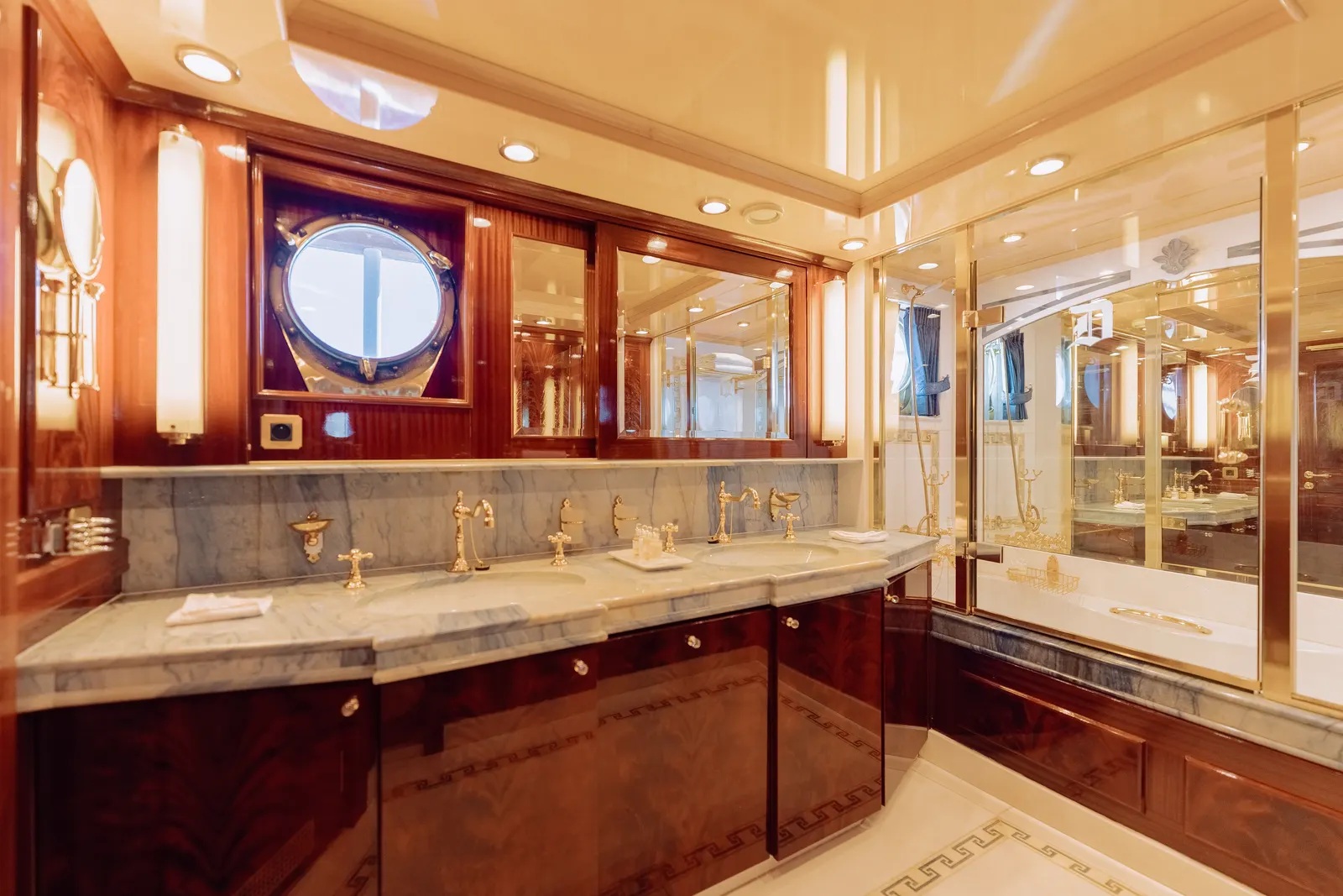 A mirrored bathroom with twin basins and a porthole above the counter.