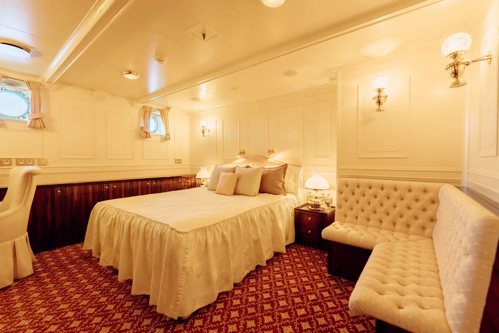 A cream double cabin with a tufted bench at the foot of the bed.