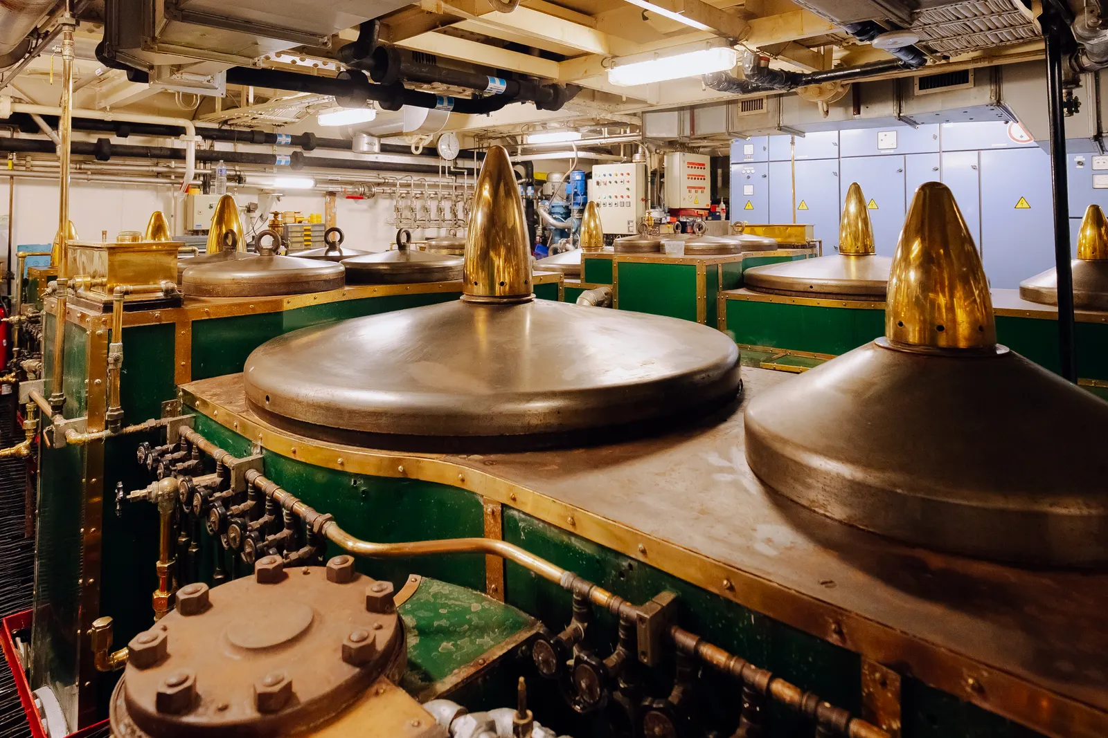 The original steam machinery in the engine room of SS Delphine, green casings under polished brass cylinder tops.