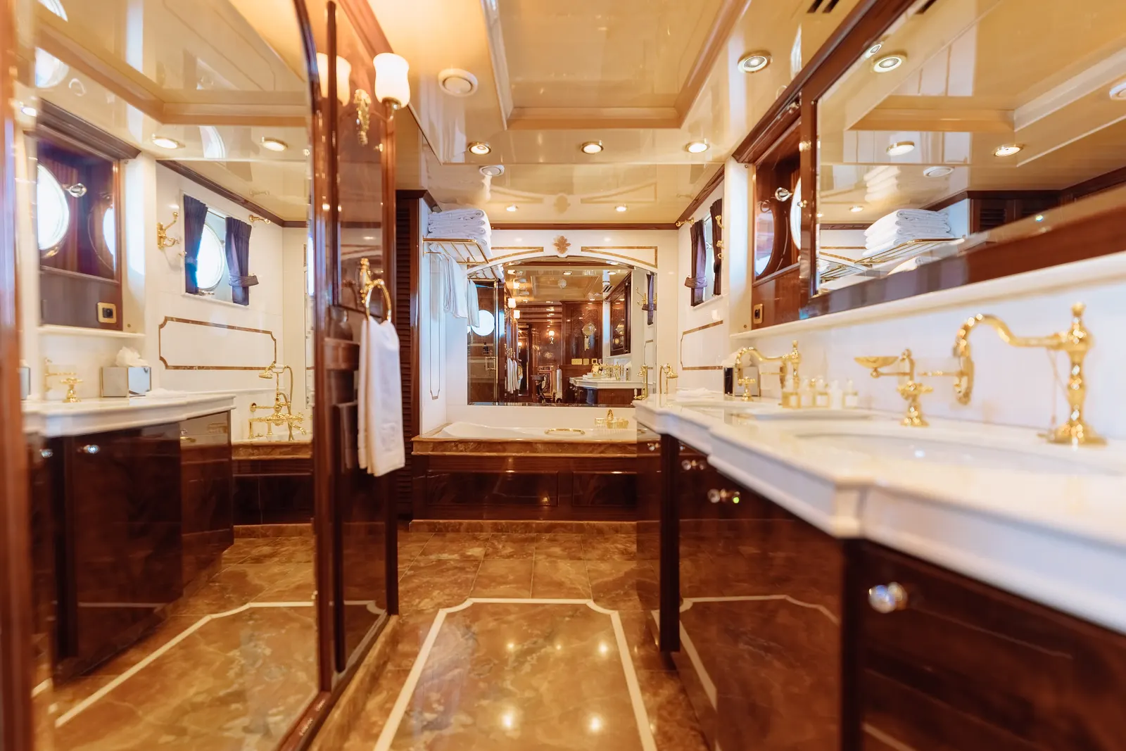 A marble bathroom with a long vanity and gold fittings.