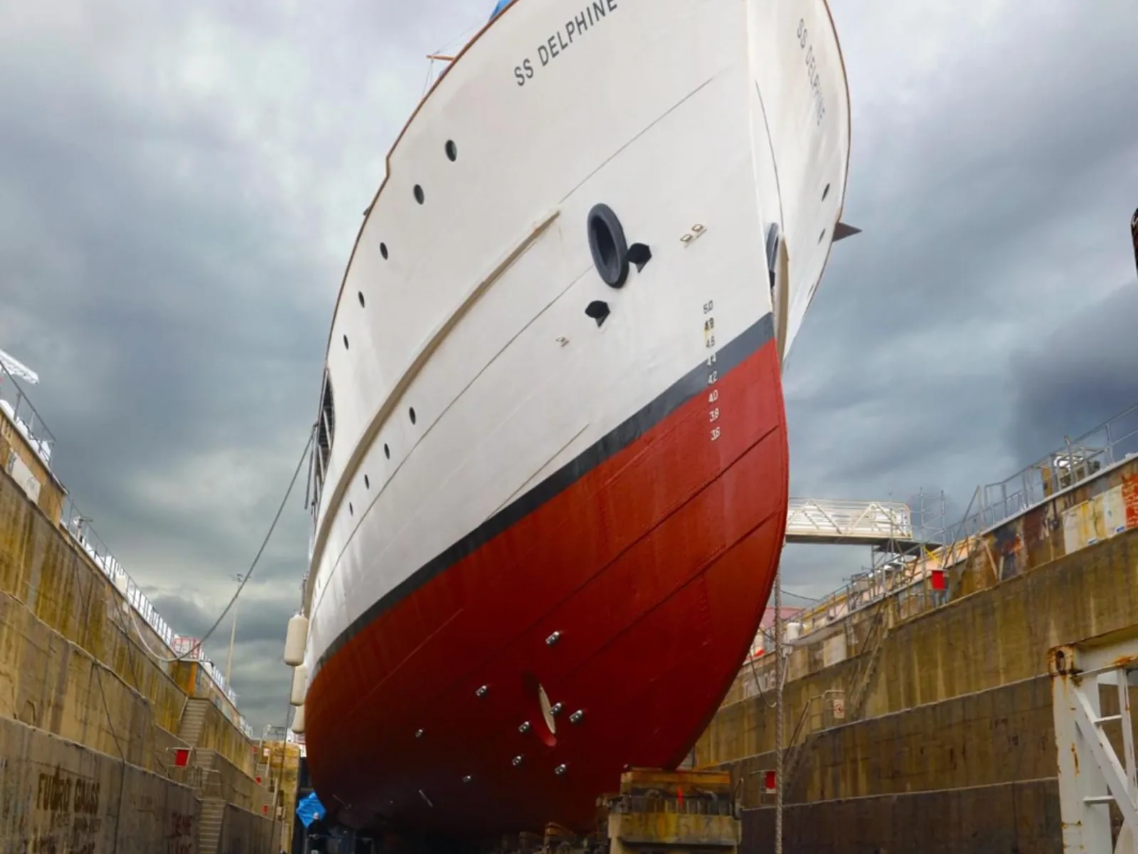 SS Delphine in dry dock at Marseille, bow rising against a heavy sky.