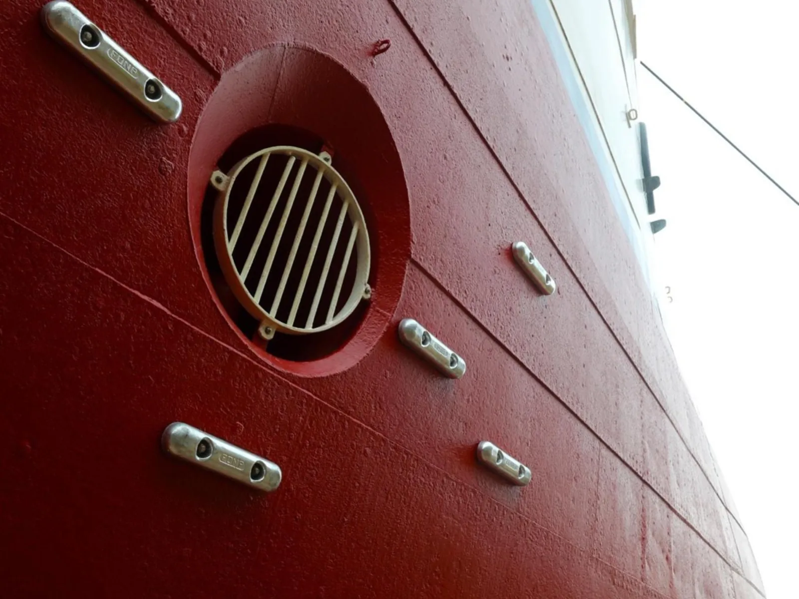 Riveted hull plating with sacrificial anodes and a sea chest grating.