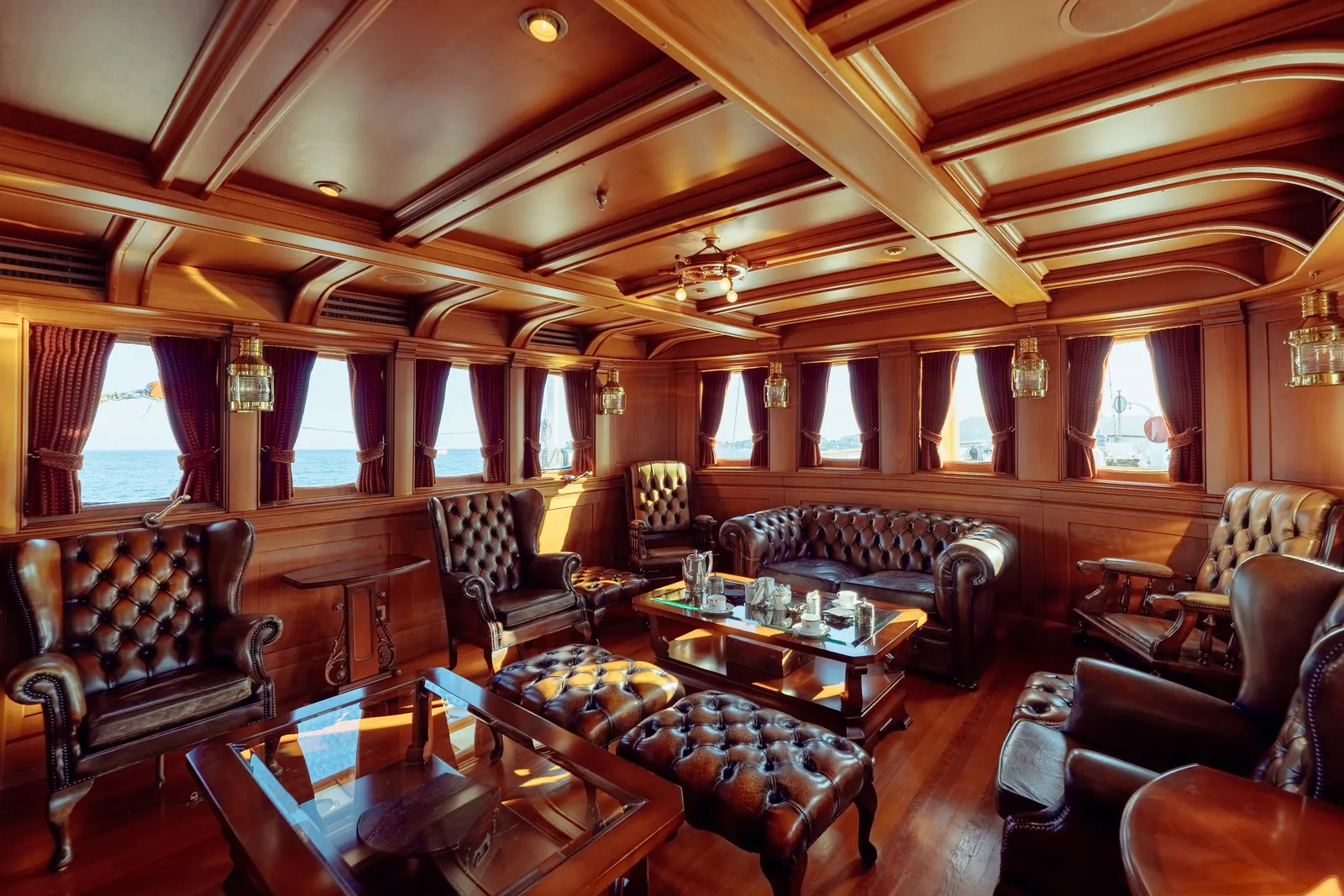 The smoking room aboard SS Delphine, panelled in timber with buttoned leather armchairs and sofas.