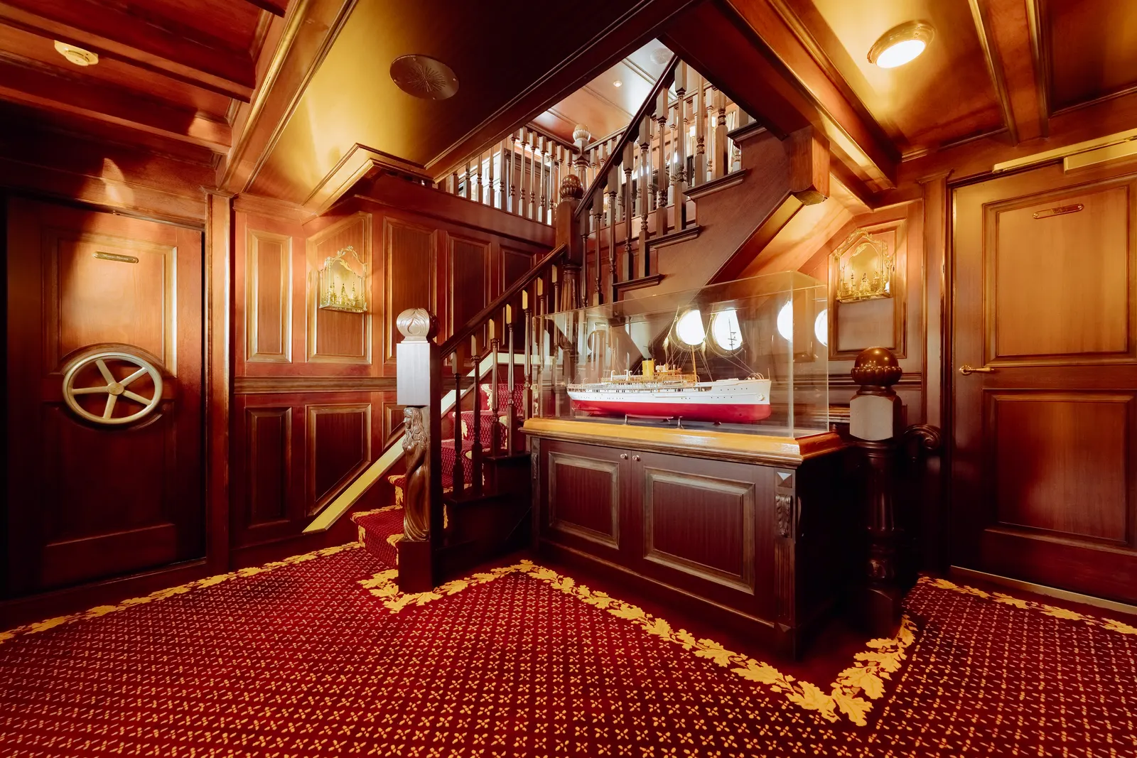 The staircase landing, with a cased model of SS Delphine against the panelling.