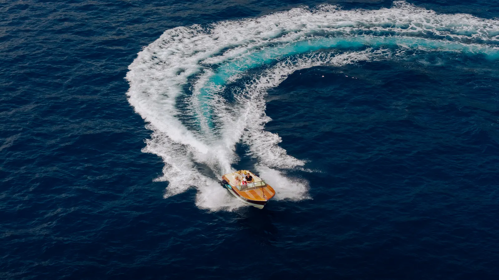 The yacht's tender carving a turn across deep blue water.